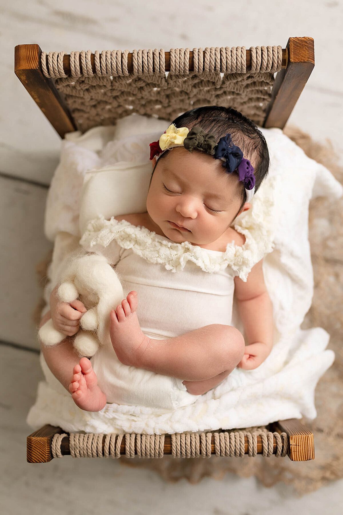 Newborn girl posed on baby bed.