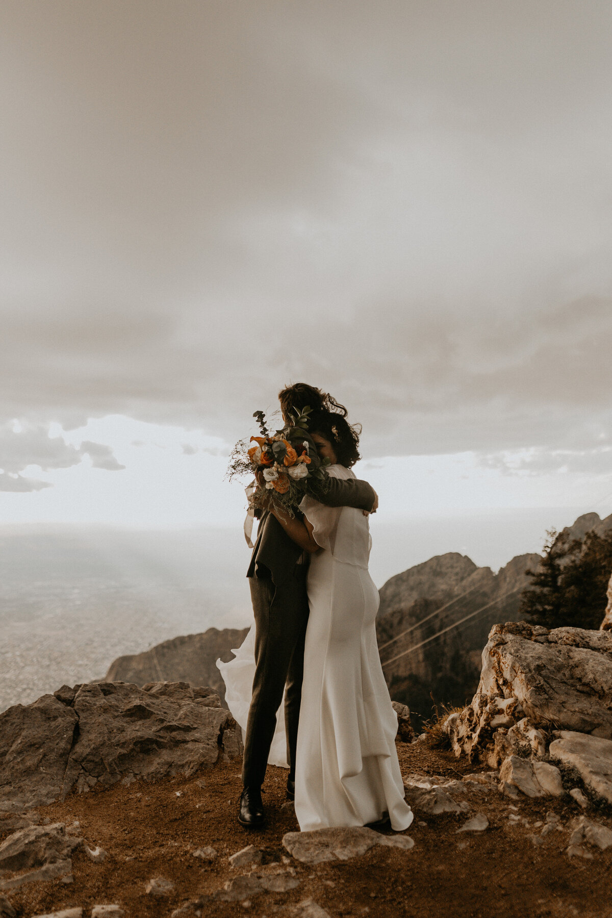 bride and groom looking down at the city of Albuquerque from the Sandia Mountains