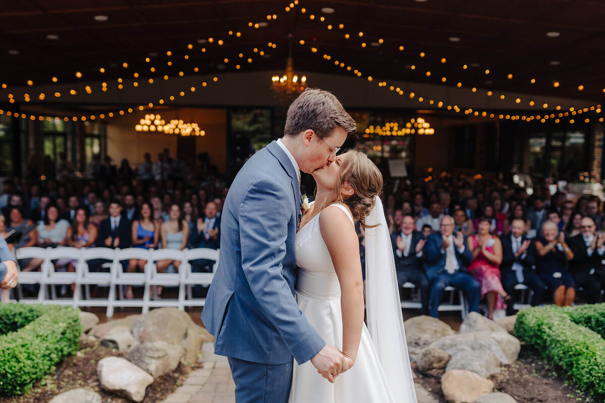 Bride and groom kissing in front of guests at Oswego wedding, NY