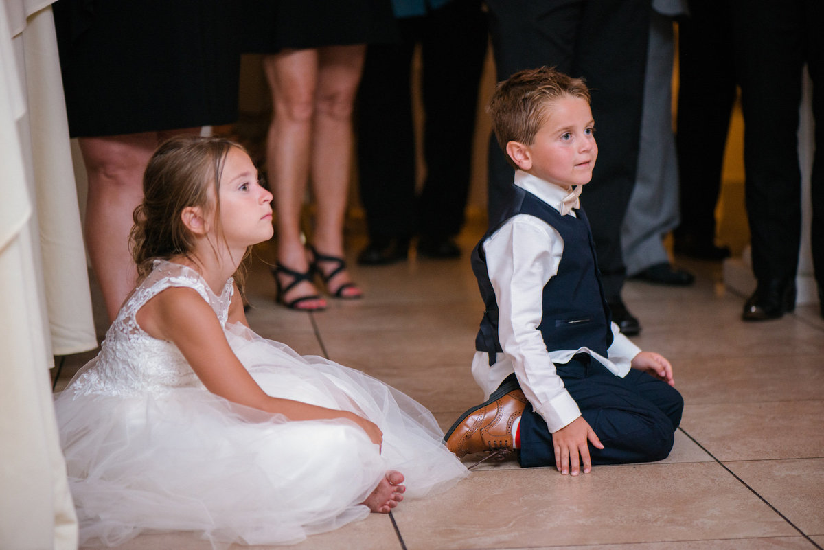 photo of ring bearer and flower girl sitting on the dance floor during wedding reception at Lombardi's on the Bay
