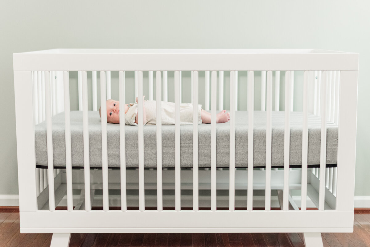 side view of newborn laying in white crib