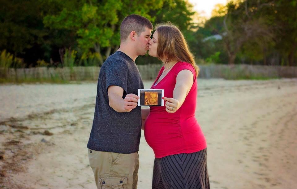 A picture of me when I was pregnant with my husband, and we're holding the sonogram and kissing.