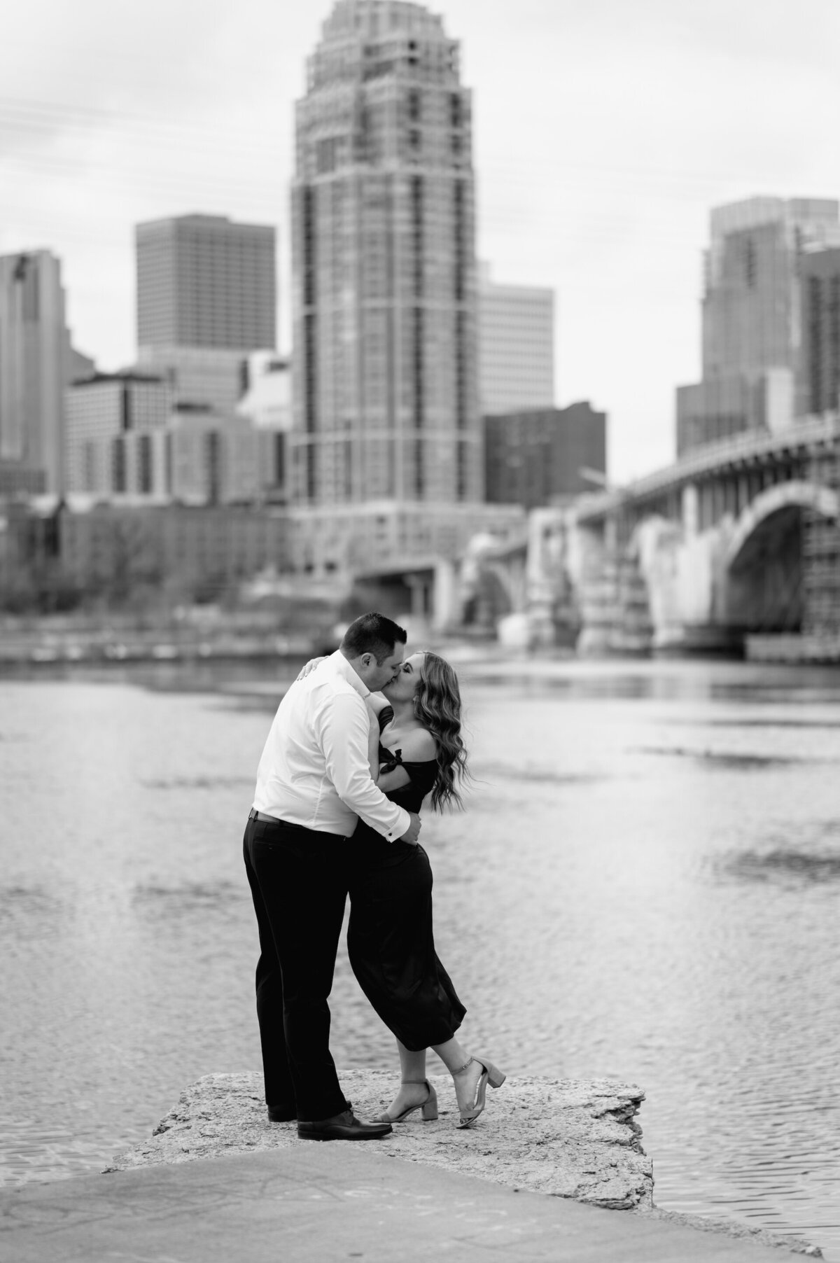 engaged couple kissing with city in the background