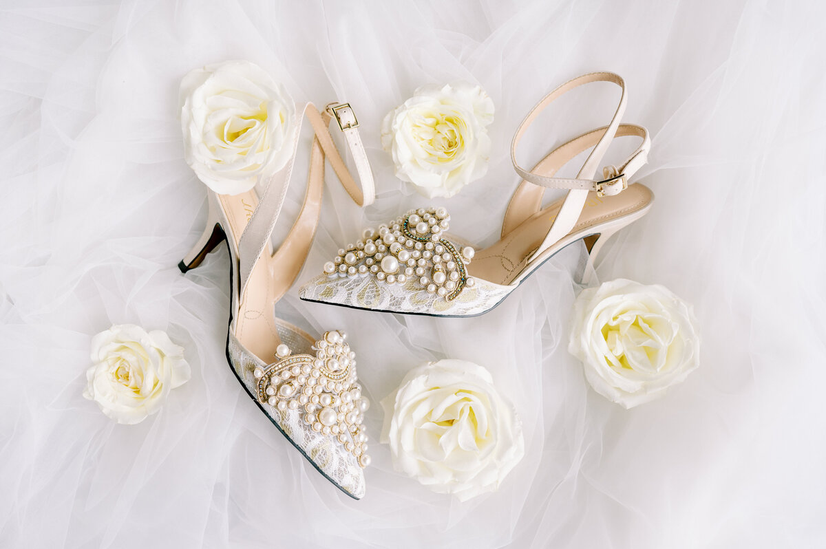 White shoes laying next to white flowers