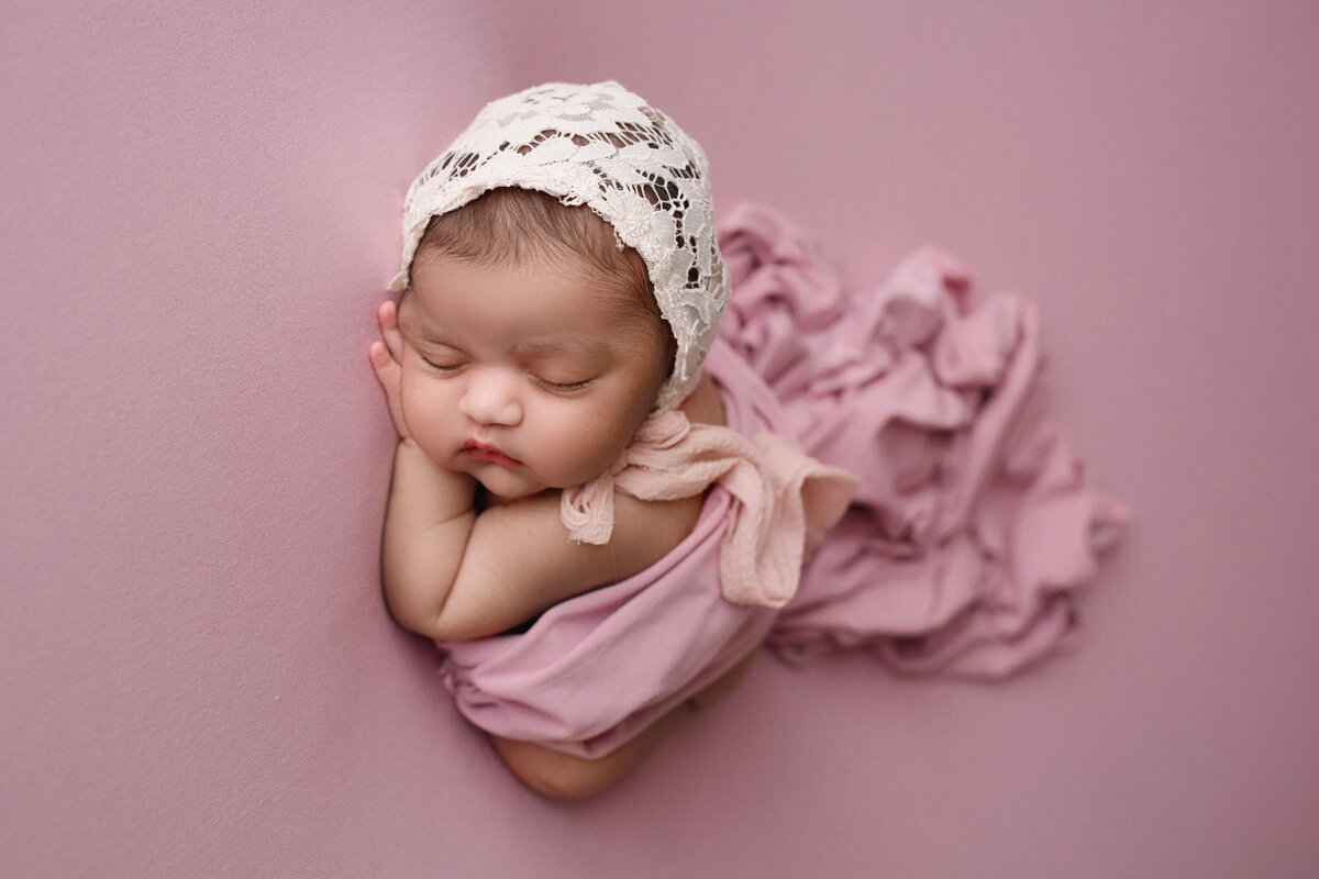 side profile of a newborn baby girl on a pink blanket