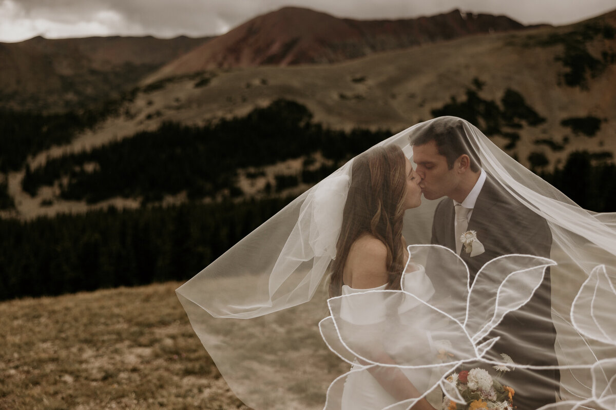 Groom and bride under veil during adventurous mountain elopement portraits.