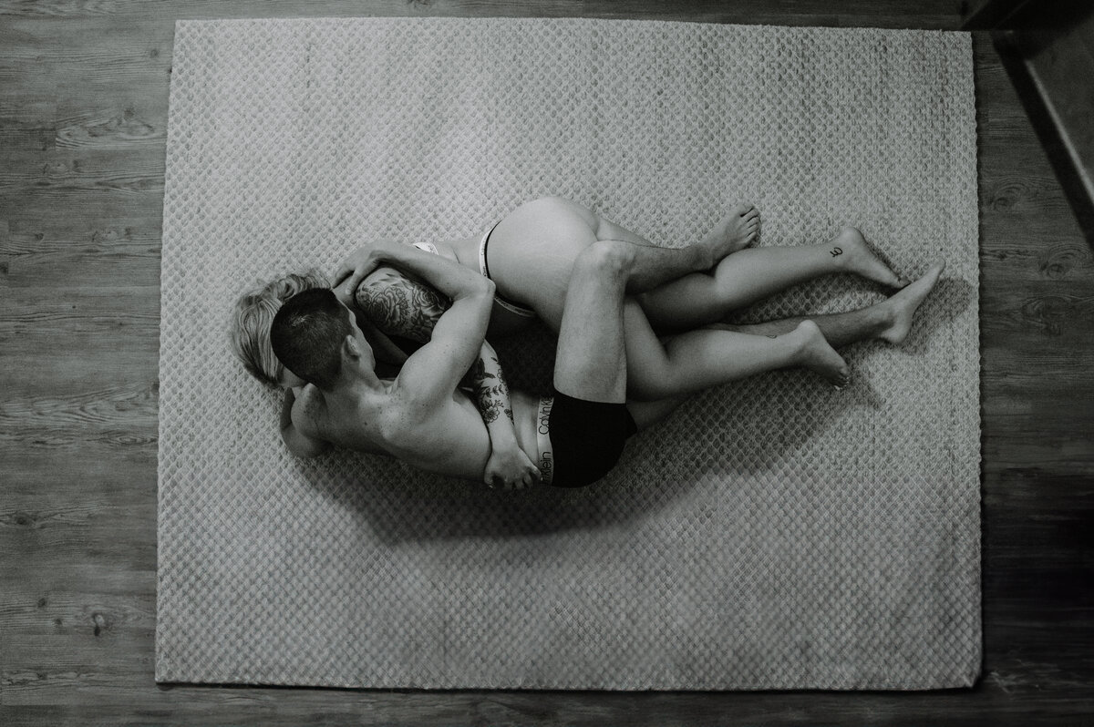 aerial view of couple lying on rug in underwear embracing . graphic added for pieces of couple breaking apart and coming back together.