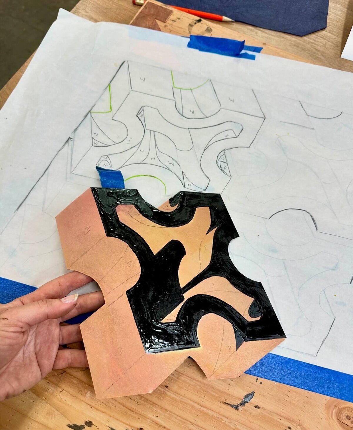 A copper plate with black asphaltum zones numbered to match a detailed planning sheet for tonal step etching.