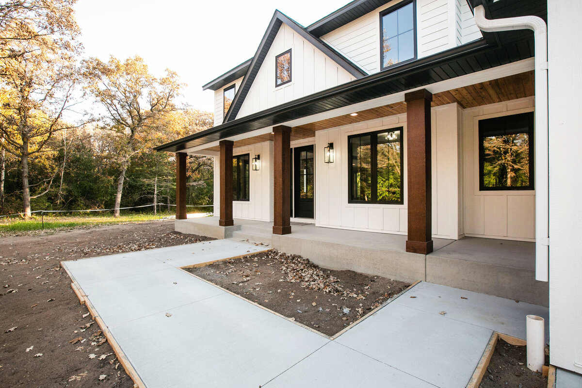 Exterior view of custom home in Big Lake Township, Minnesota with farmhouse details, cream siding, wood pillars and front porch built by Cornerstone Custom Builds