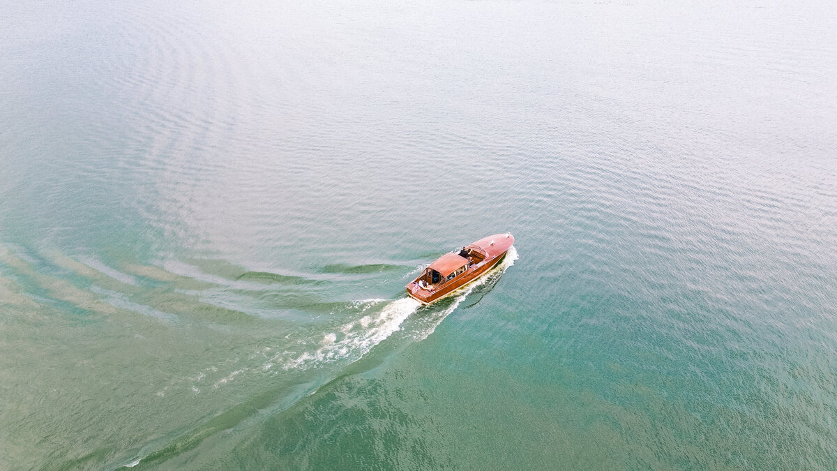 Engaged couple sits on Reynolds wood Lake Oconee boat moving across the colorful water
