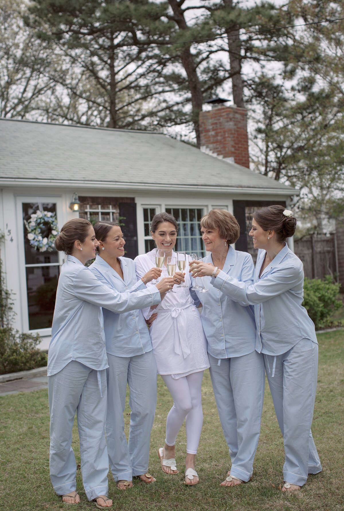 Bride and Bridesmaids cheer in baby blue pajamas during Cape Cod wedding day.