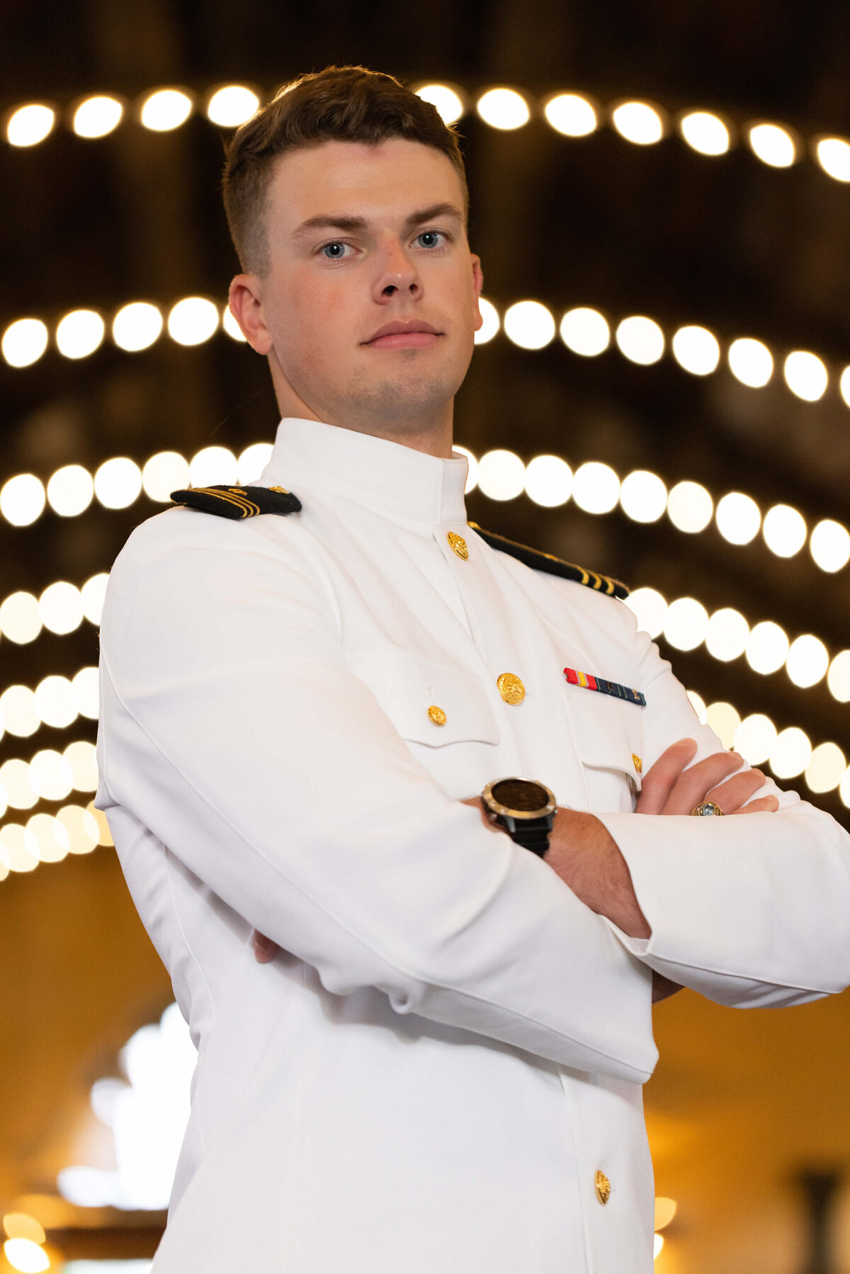 US Navy Officer in Dhalgren Hall lights in white uniform for senior photography in Annapolis, Maryland.