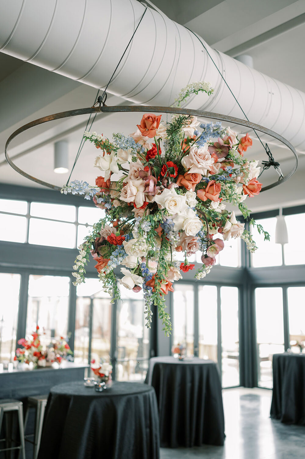 Modern floral chandelier filled with roses, delphinium, and greenery, designed for a modern wedding inspiration shoot.