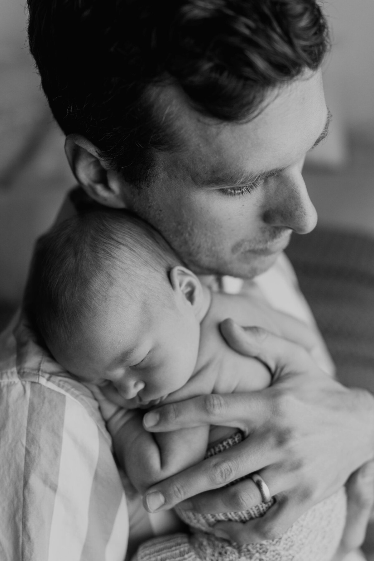 black and white fine art image of father protectively holding his newborn baby boy
