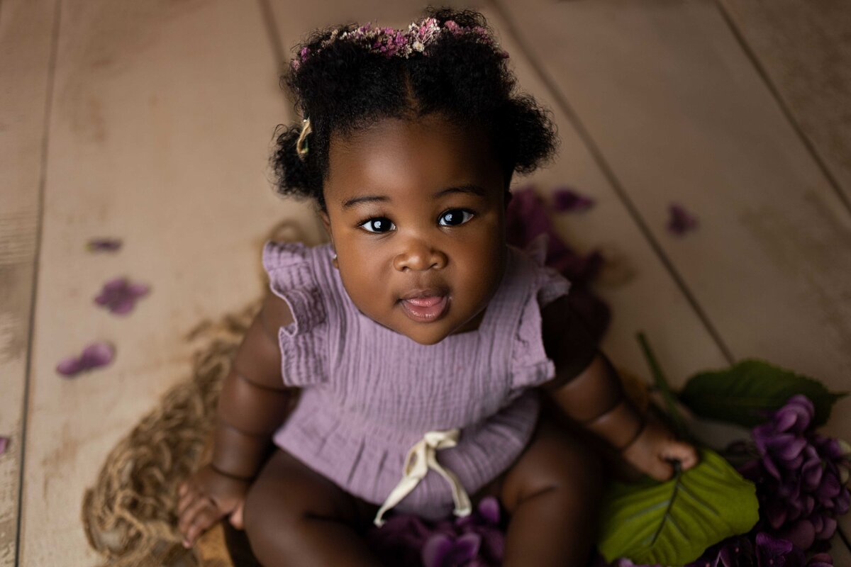 6 month old baby girl in purple outfit smiling at camera
