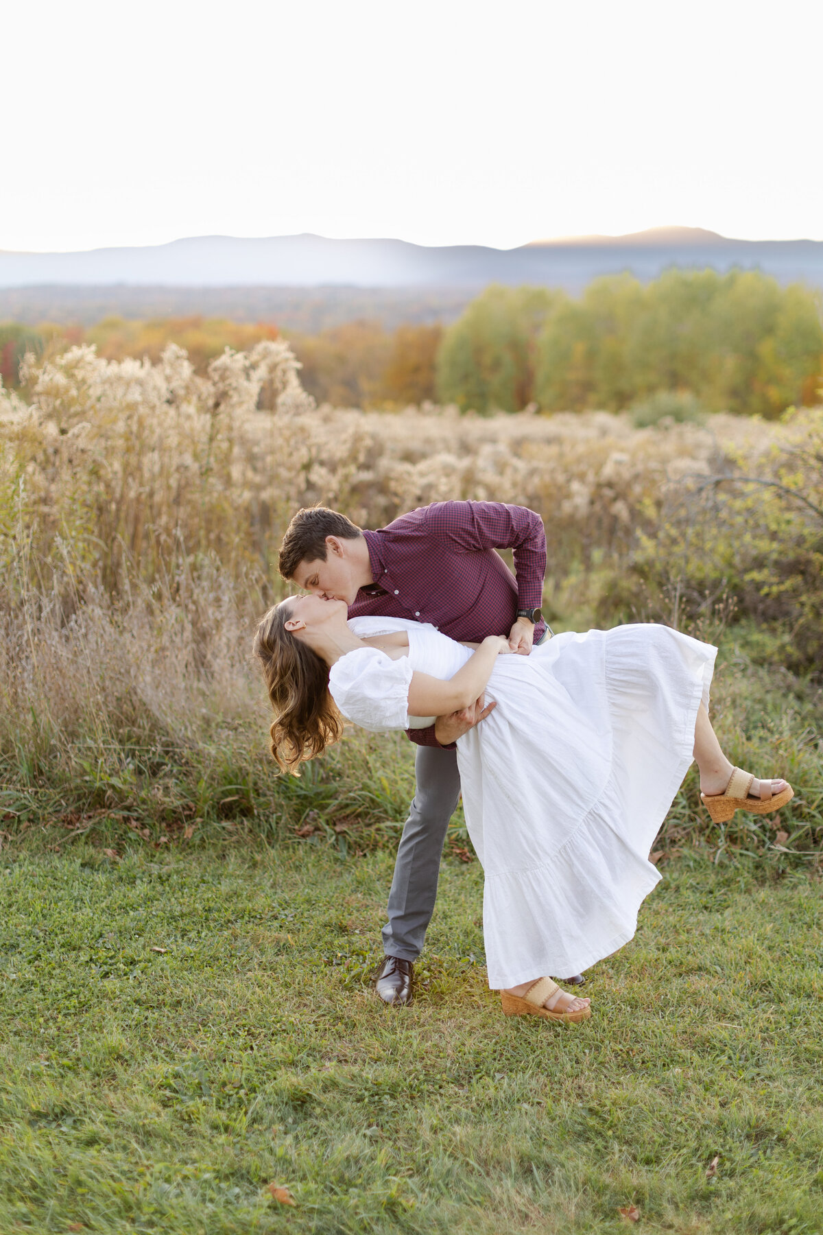 Soon to be bride and groom share a dip kiss with the sun setting behind Catskill mountains 