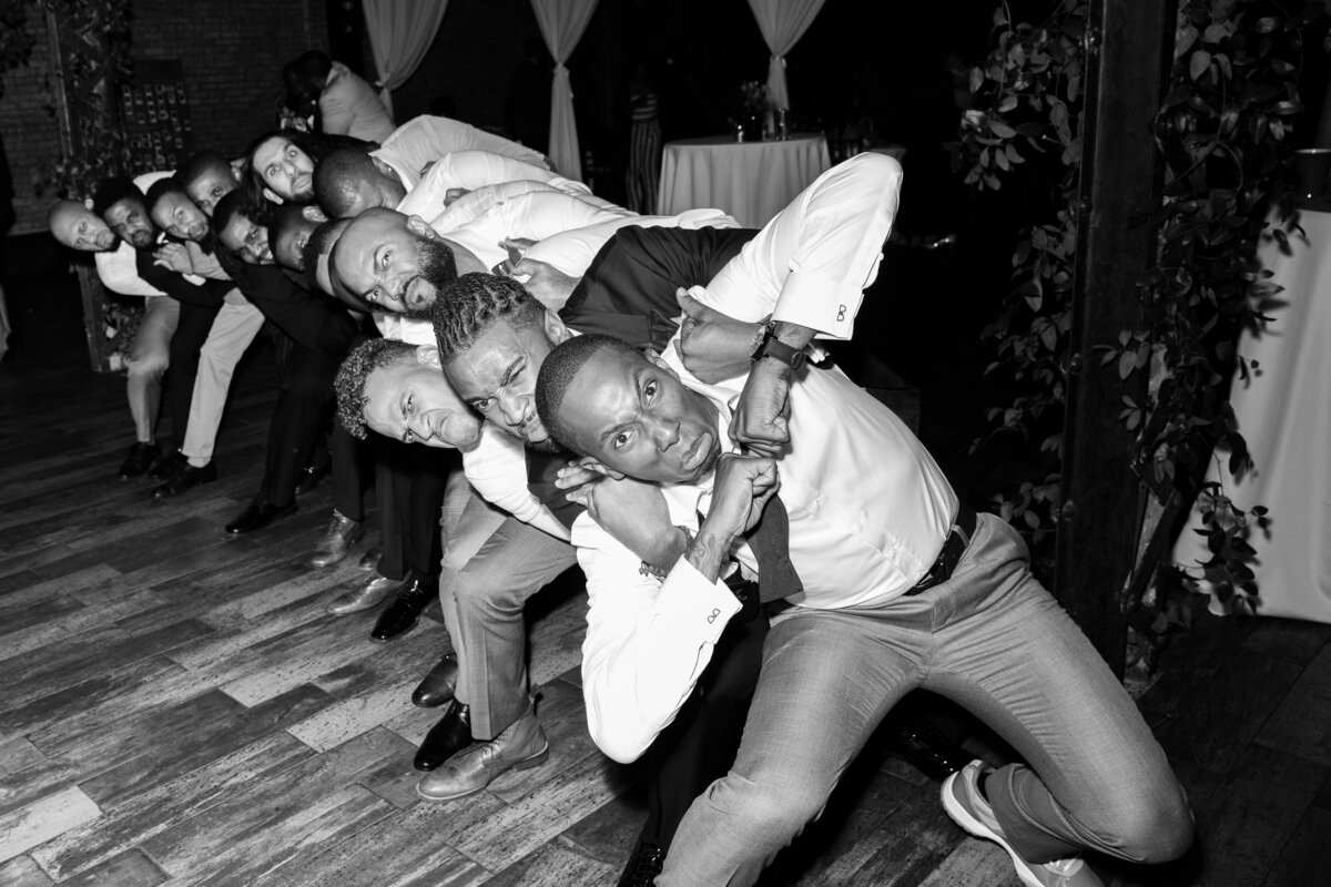 Black and white photo of wedding guests dancing in a line.