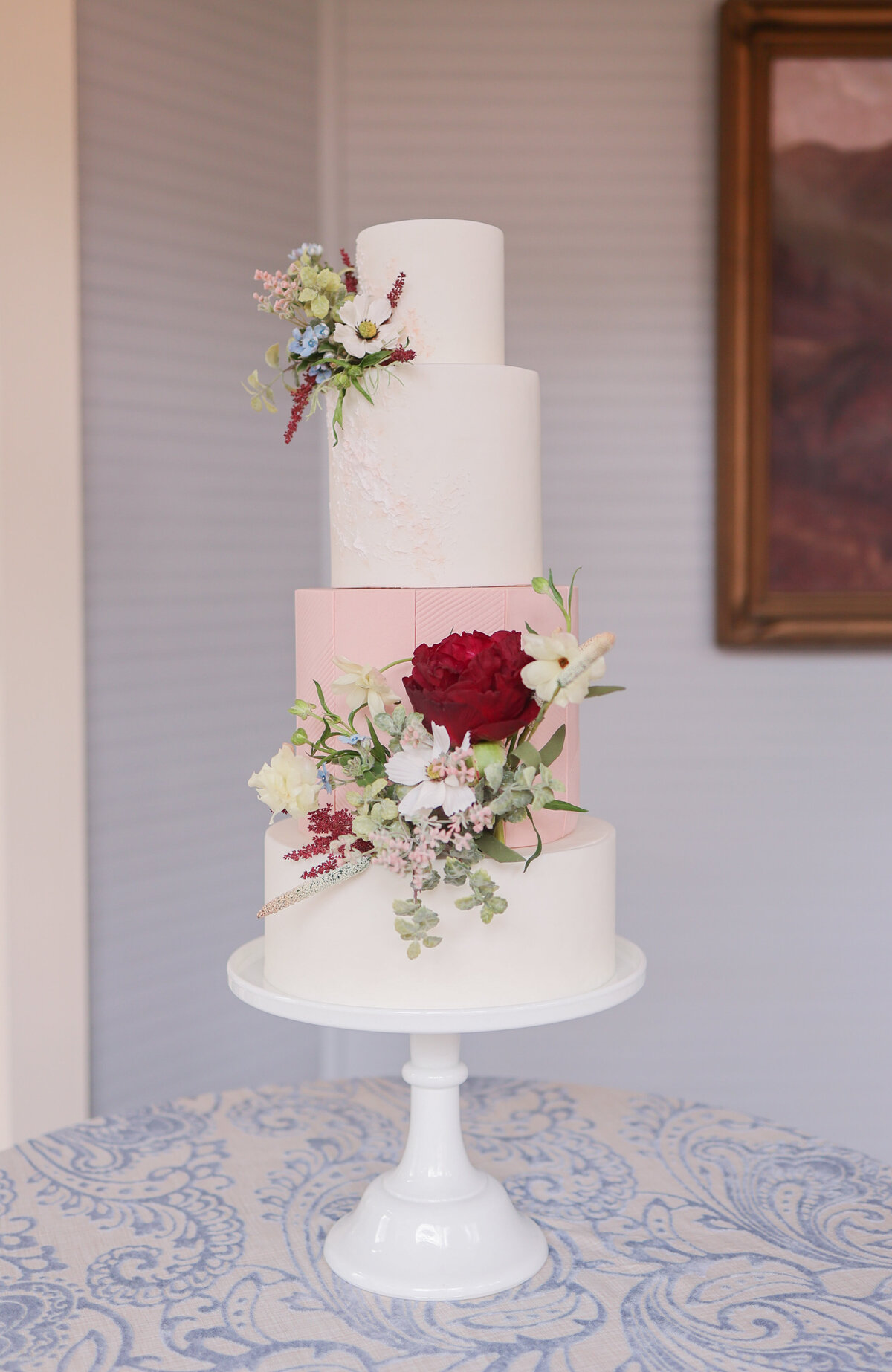 white and pink cake with four tiers and florals decorating the cake