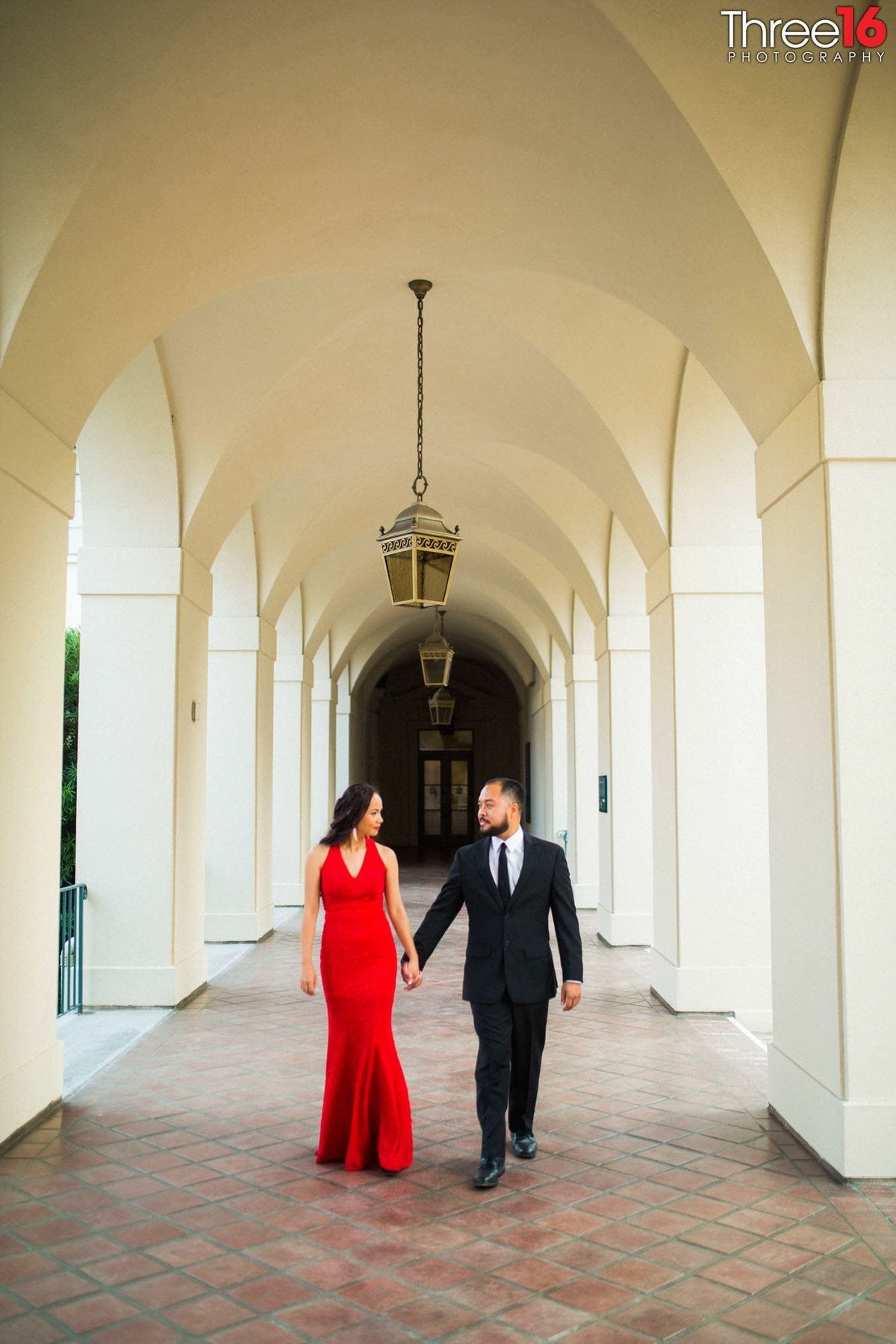 Engaged couple walk hand in hand down the Pasadena City Hall corridor