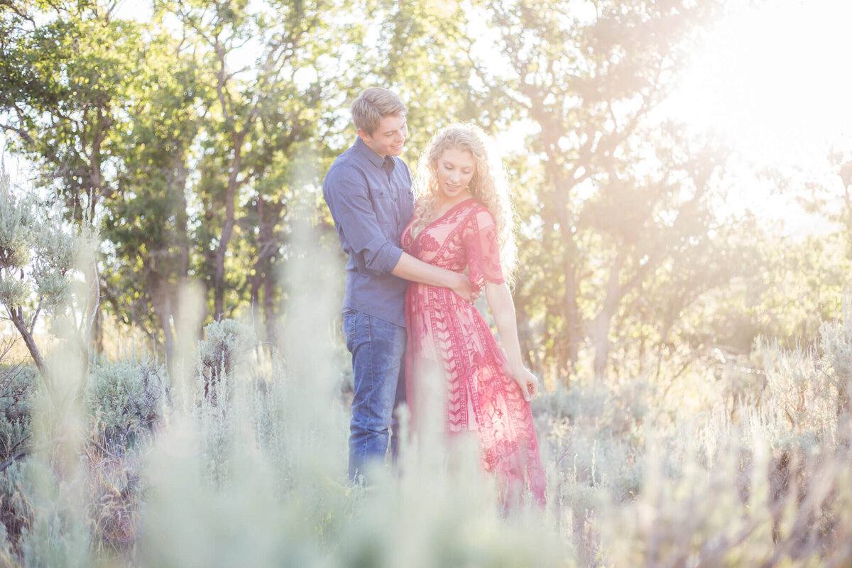 an engaged wedding couple admiring a red dress in the sunset