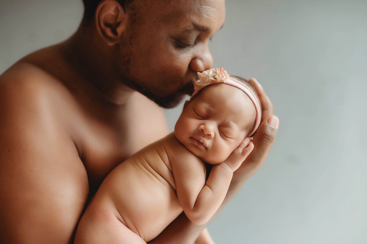 Father embraces newborn baby during newborn photoshoot in Asheville, NC.