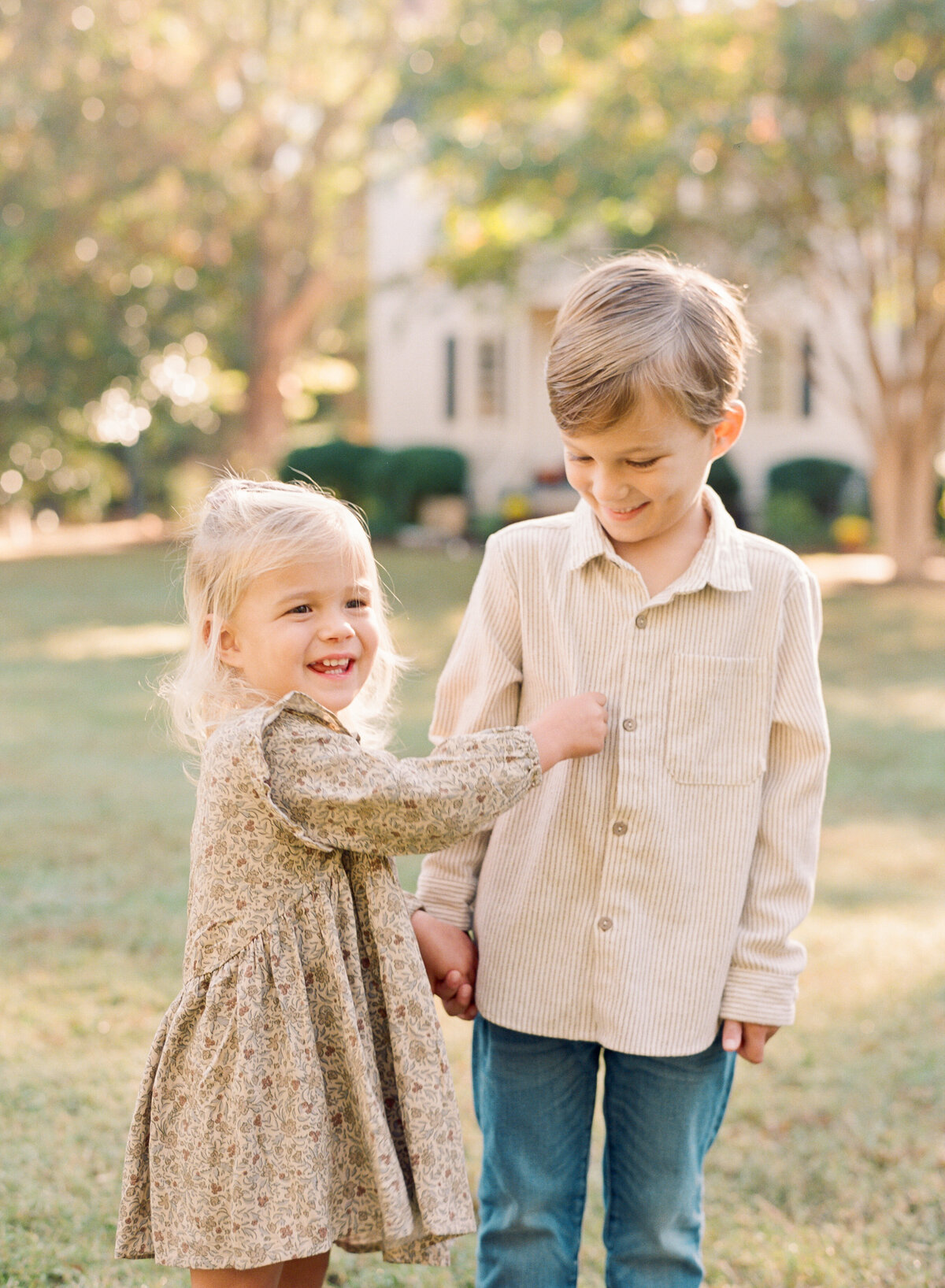 Siblings tickle and play during their fall family photos in Raleigh NC. Family walking during their family portrait session in Wake Forest, NC. Photographed by Raleigh family photographer A.J. Dunlap Photography.