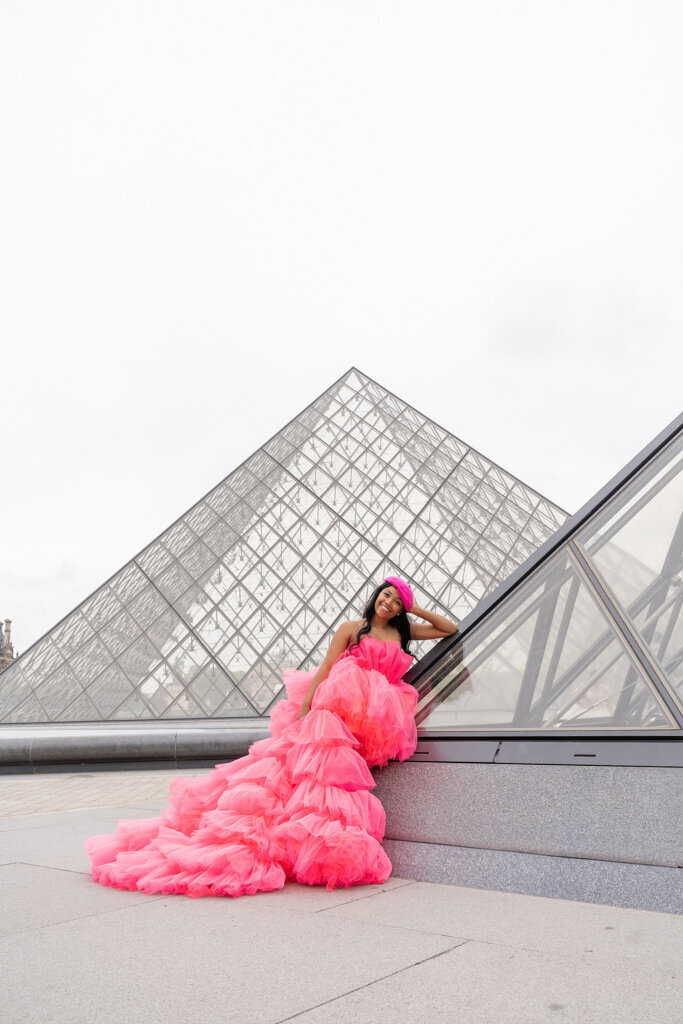 Luxury portrait session at Louvre pyramid with woman in fuchsia pink fluffy dress and matching beret