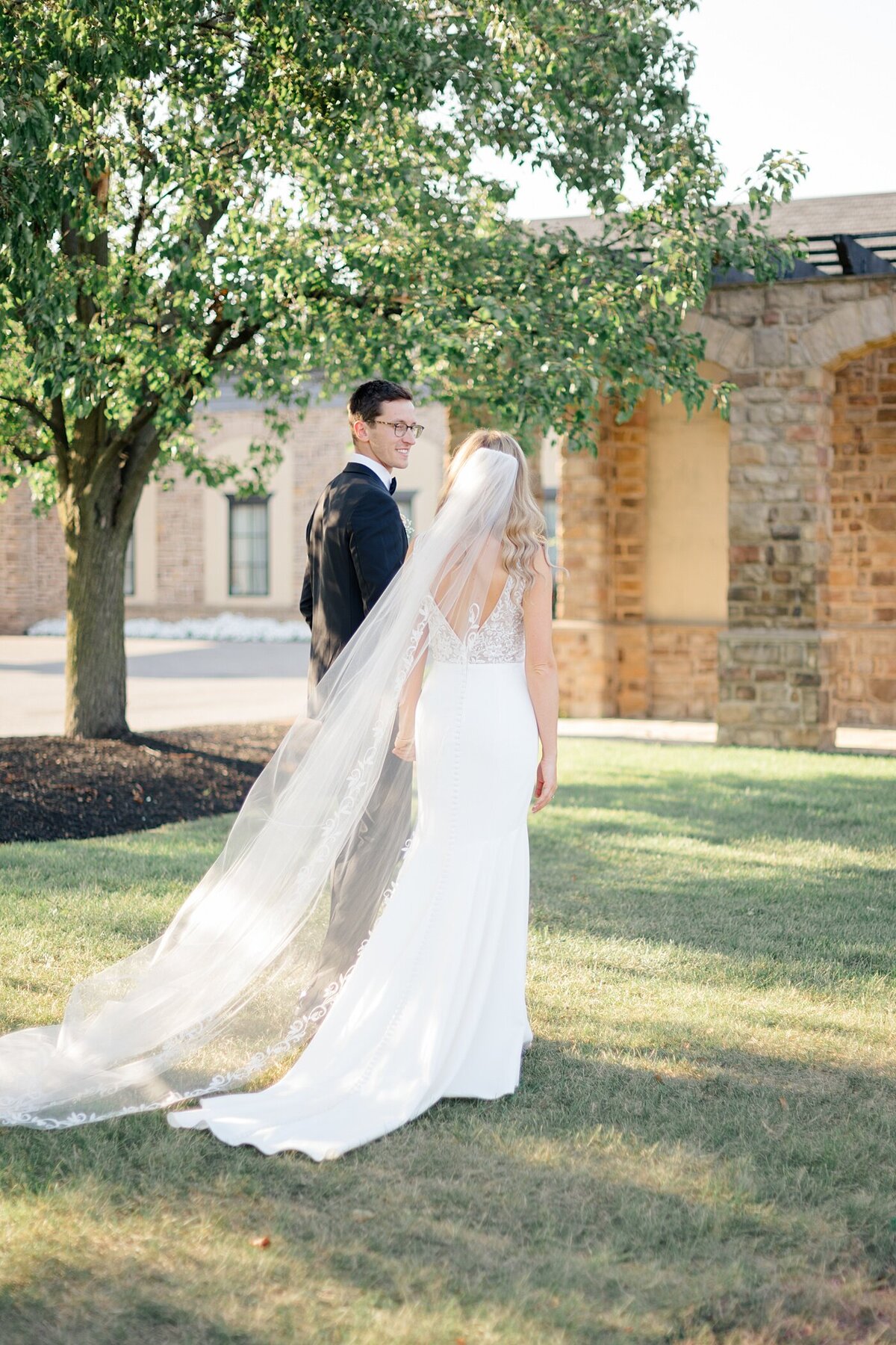 candid wedding photo by Columbus wedding  photographer  with bride and groom holdin ghands and walking through a lawn at the Pinnacle