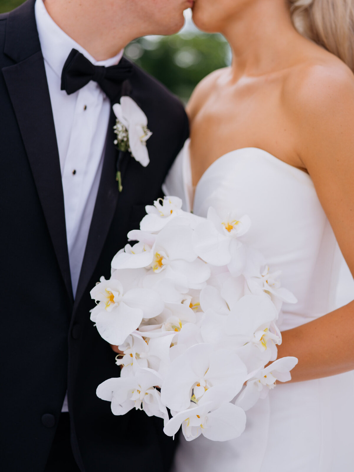 White orchid bouquet for the bride and a black tux for the groom