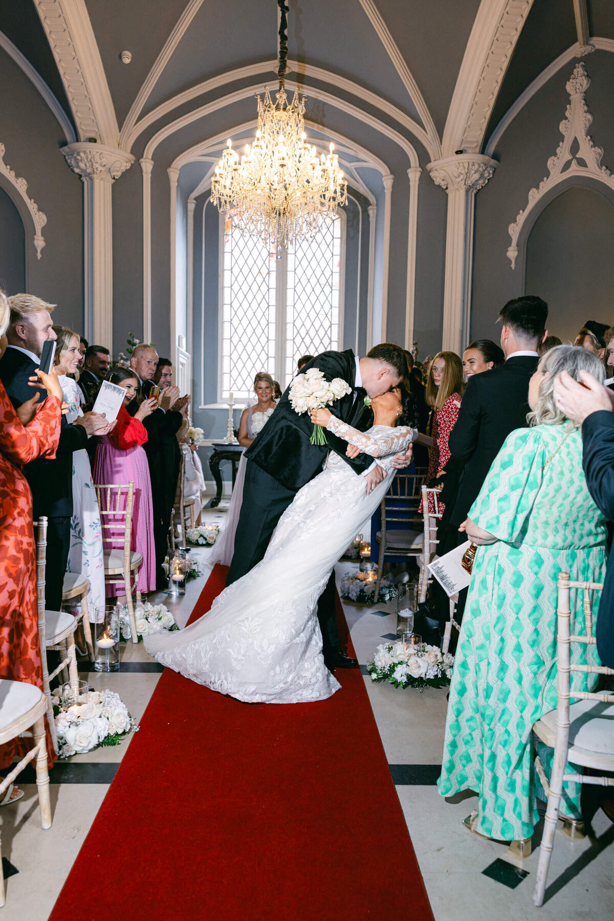 A wedding photo of the bride and groom kissing half way dwon the aisle after they got married at Luttrellstown Castle
