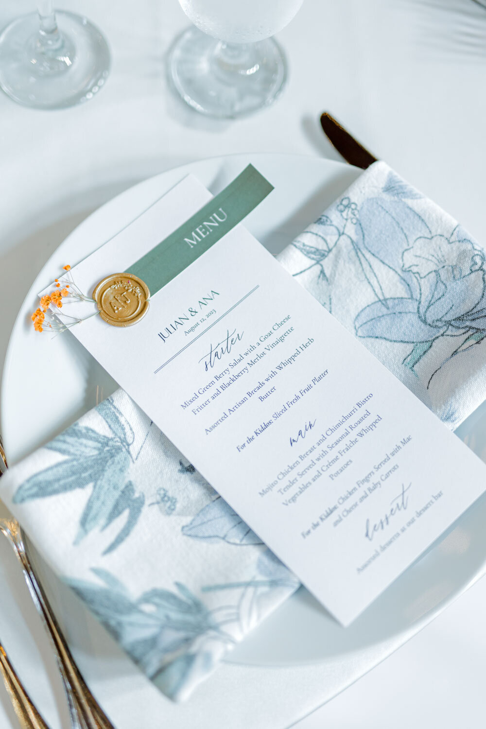 Wedding menu on a plate with floral napkin and wax seal