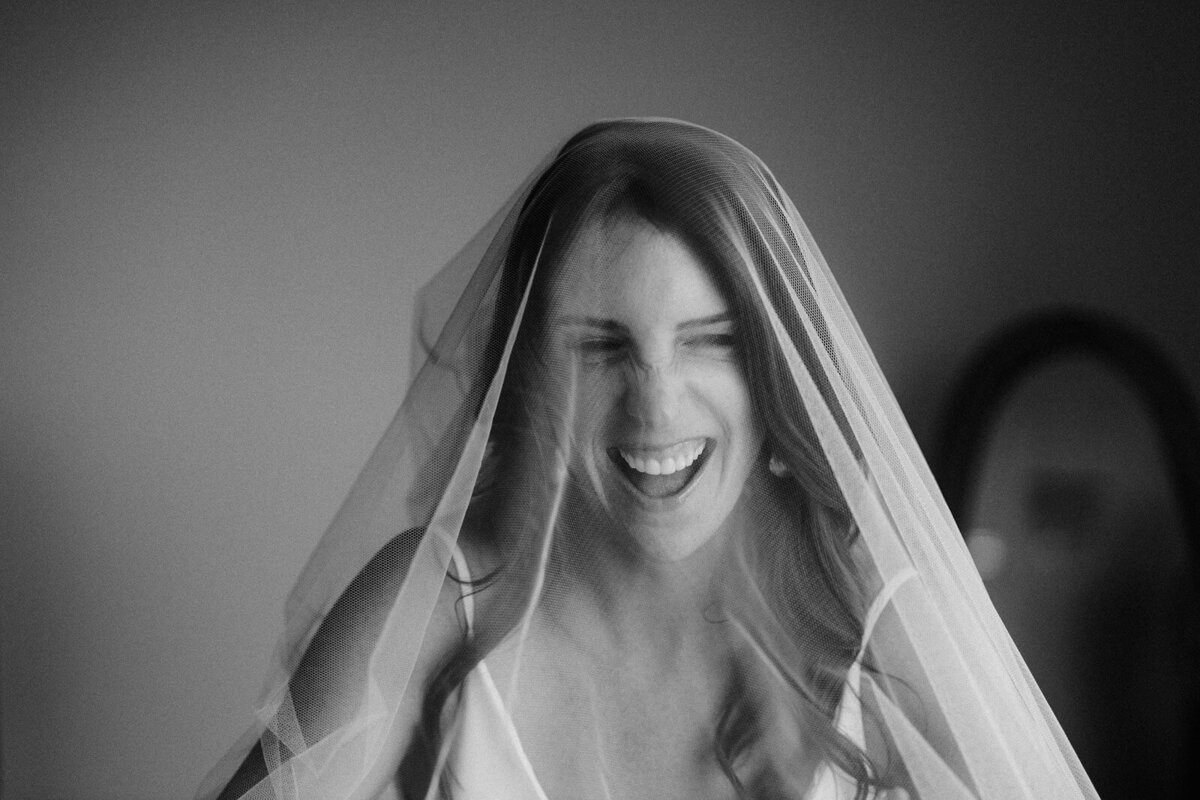 Black and white close-up view of the bride wearing her veil, smiling with mouth wide-open, at Wianno Club, Cape Cod, MA.