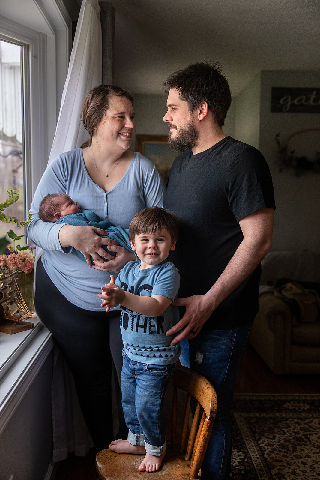 Family Poses With New Baby Beside Window in Home