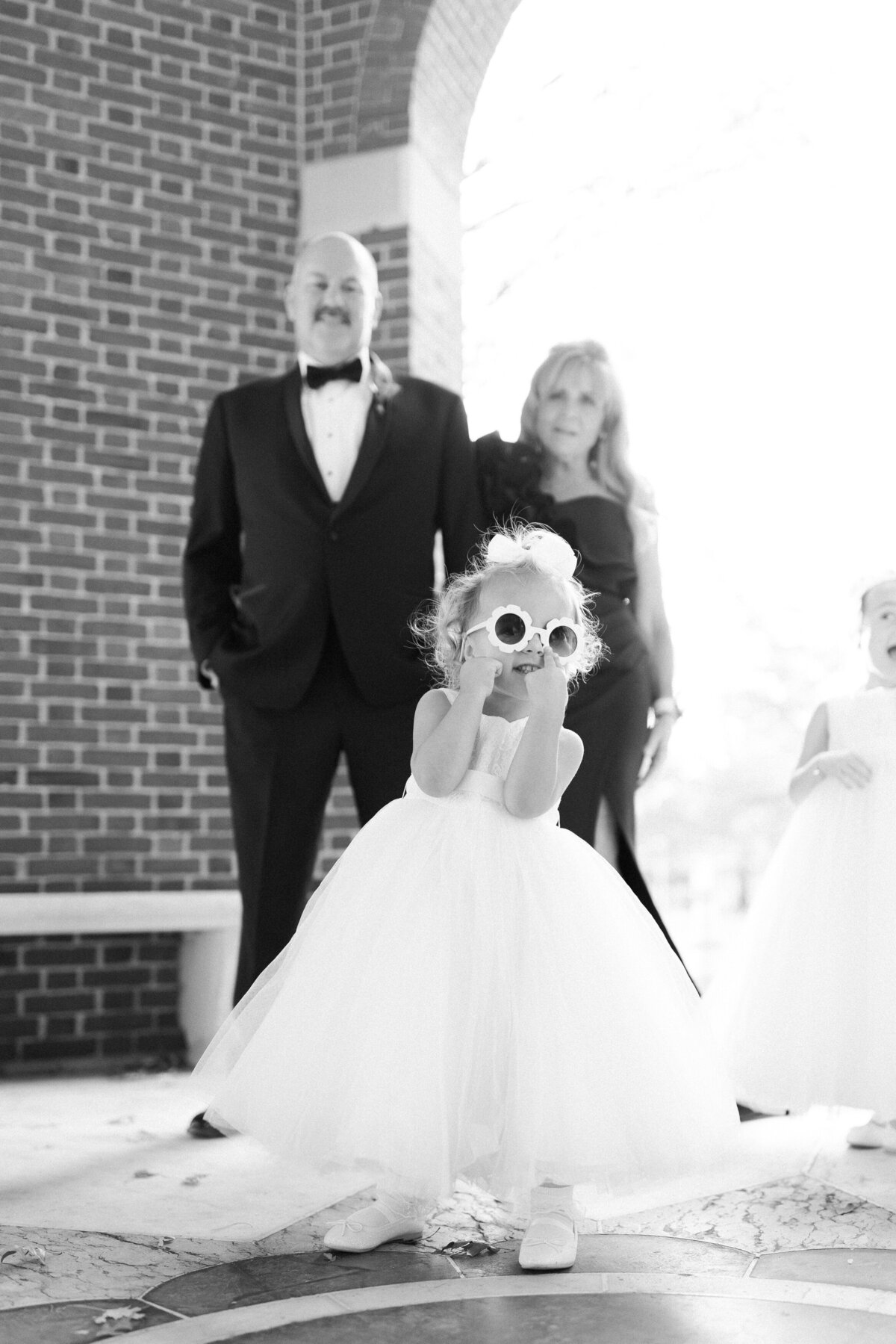 Small flower girl walks down the aisle in sunglasses