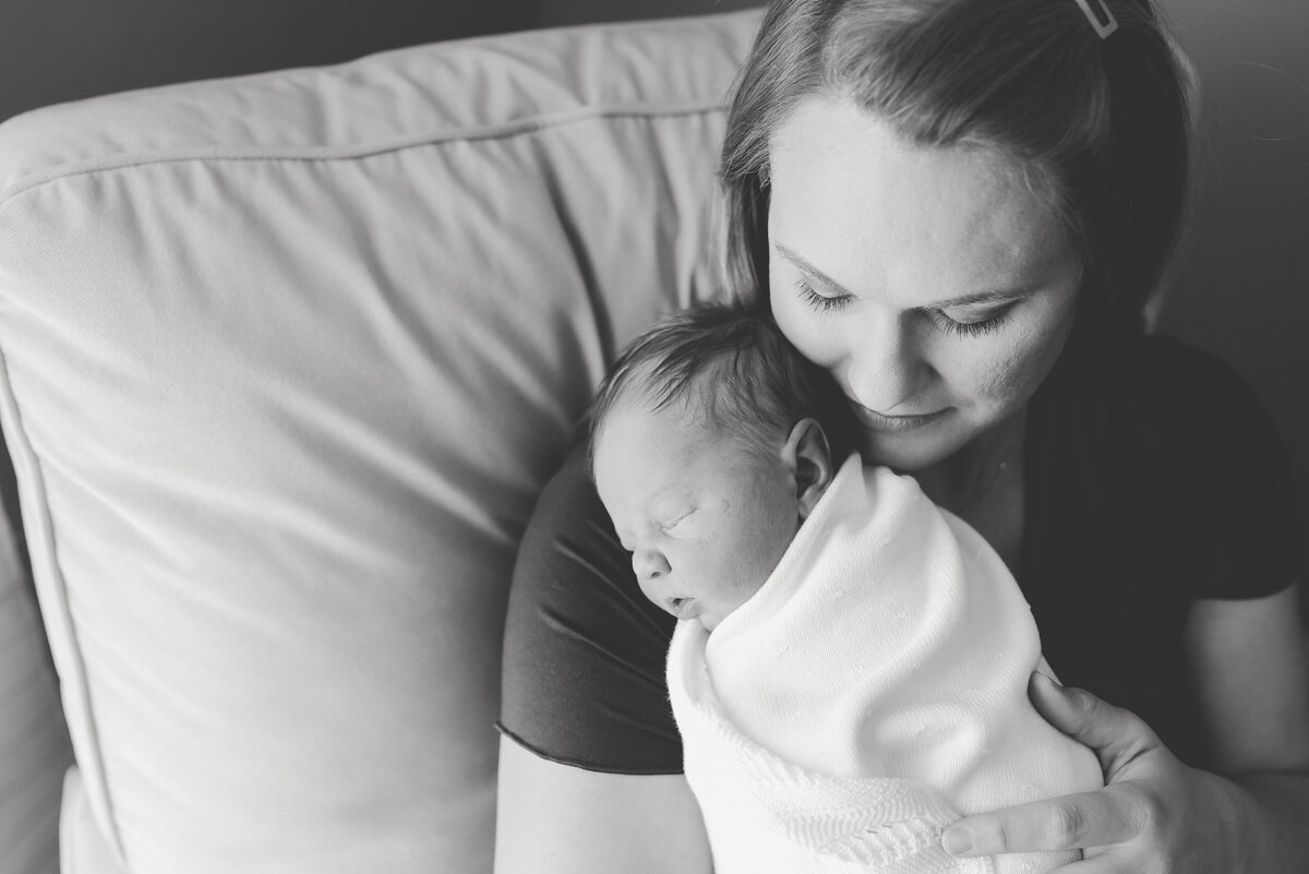 Beautiful lifestyle newborn photography: Natural light black and white of newborn boy on his mothers shoulder in nursery