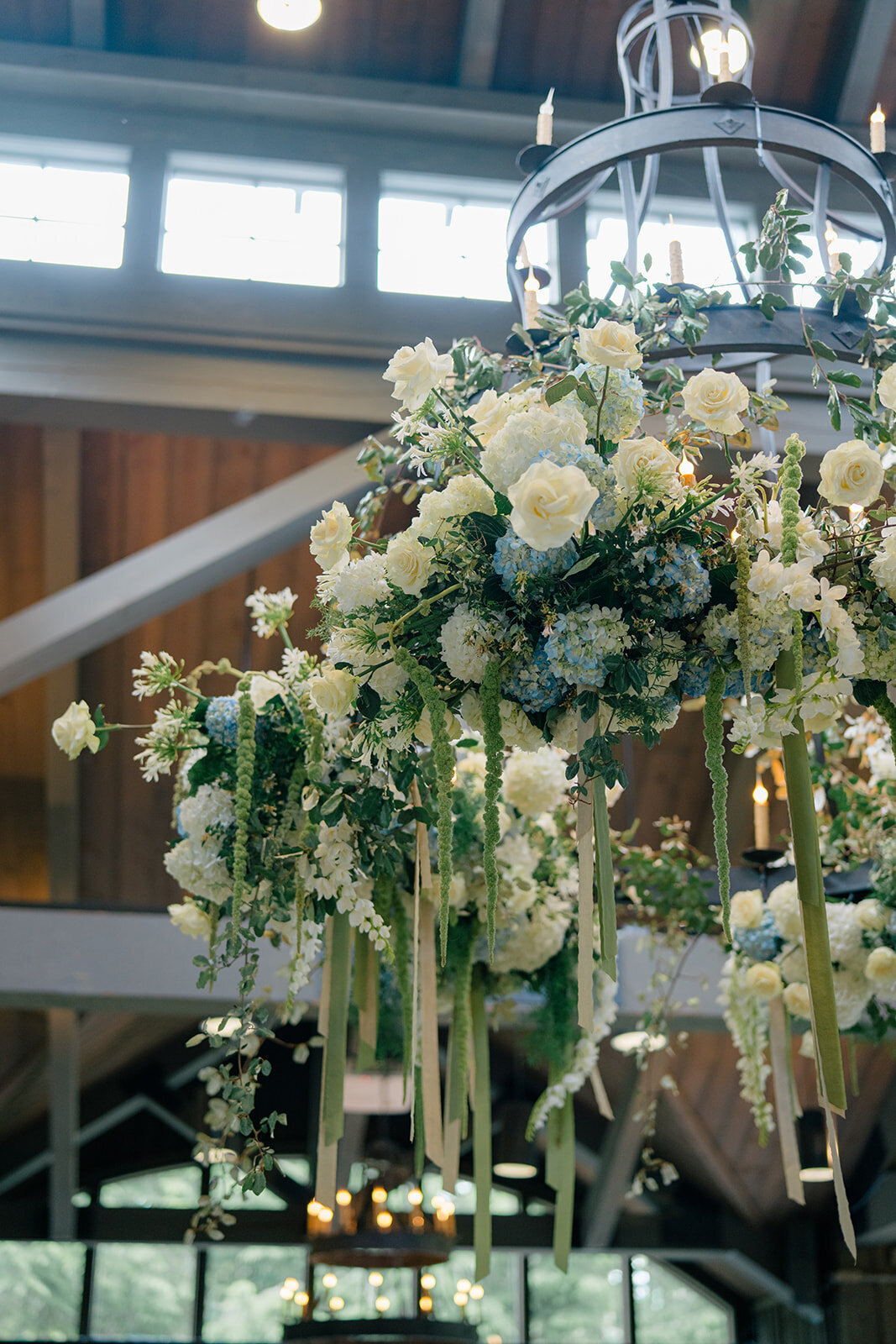 Hanging floral chandelier with white roses and cascading greenery at mountain wedding reception.”