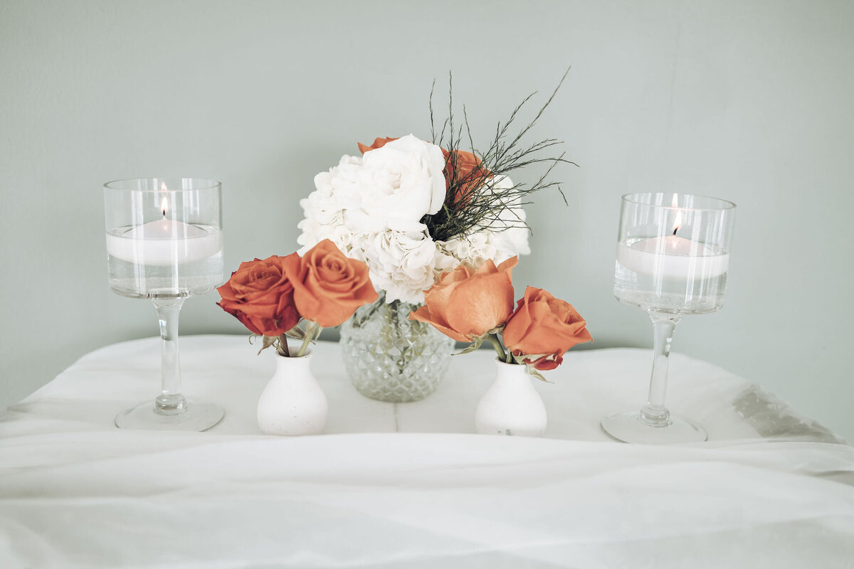 orange roses in white vases