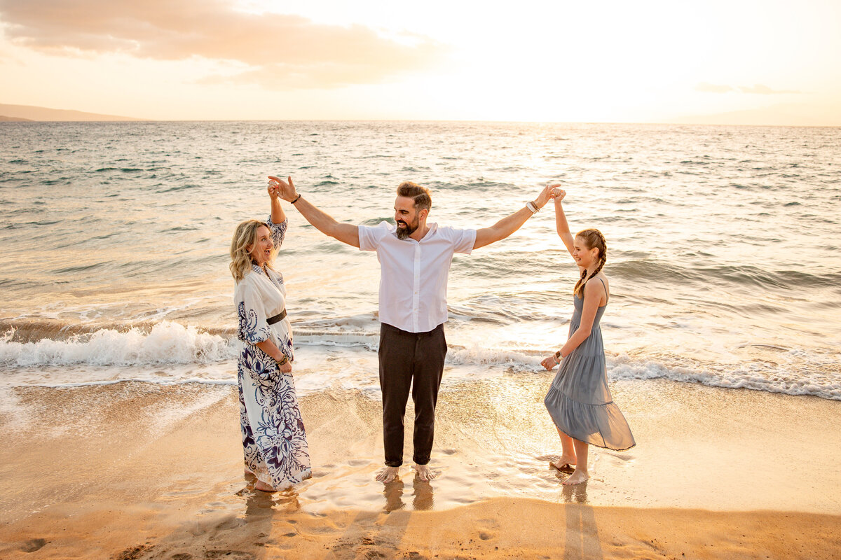 Maui Family Photographers capture husband holding up hands and spinning daughter and wife