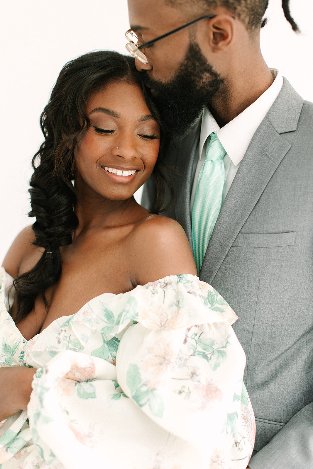 A black couple embraces. The bride wears a custom floral gown by Sarah Kolis and makeup by D Neiswender Artistry