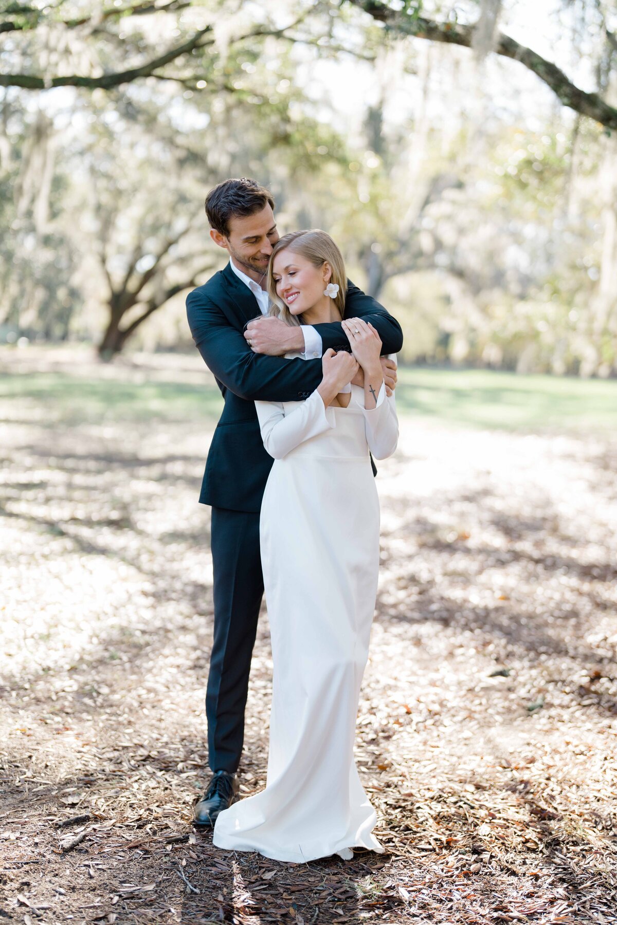 couple cuddling after wedding under the moss trees in savannah Georgia