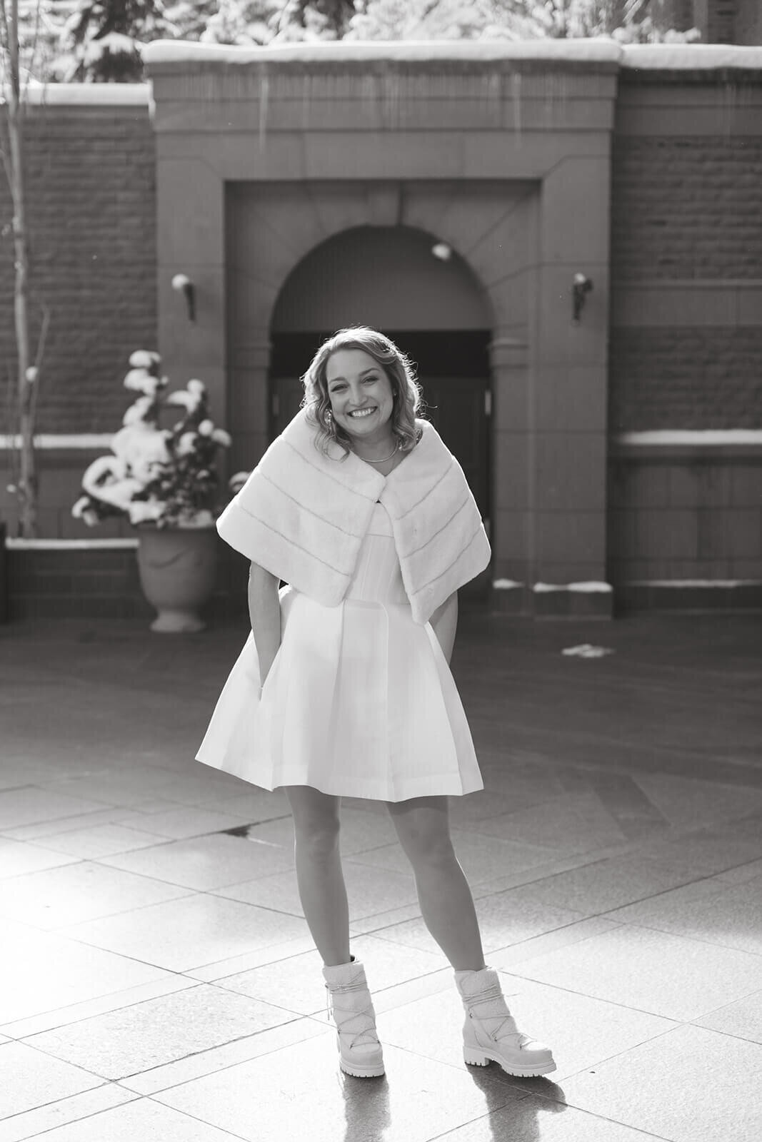 Bride in a short dress at St. Regis Aspen, posing in a scenic outdoor setting with lush greenery and mountain views.