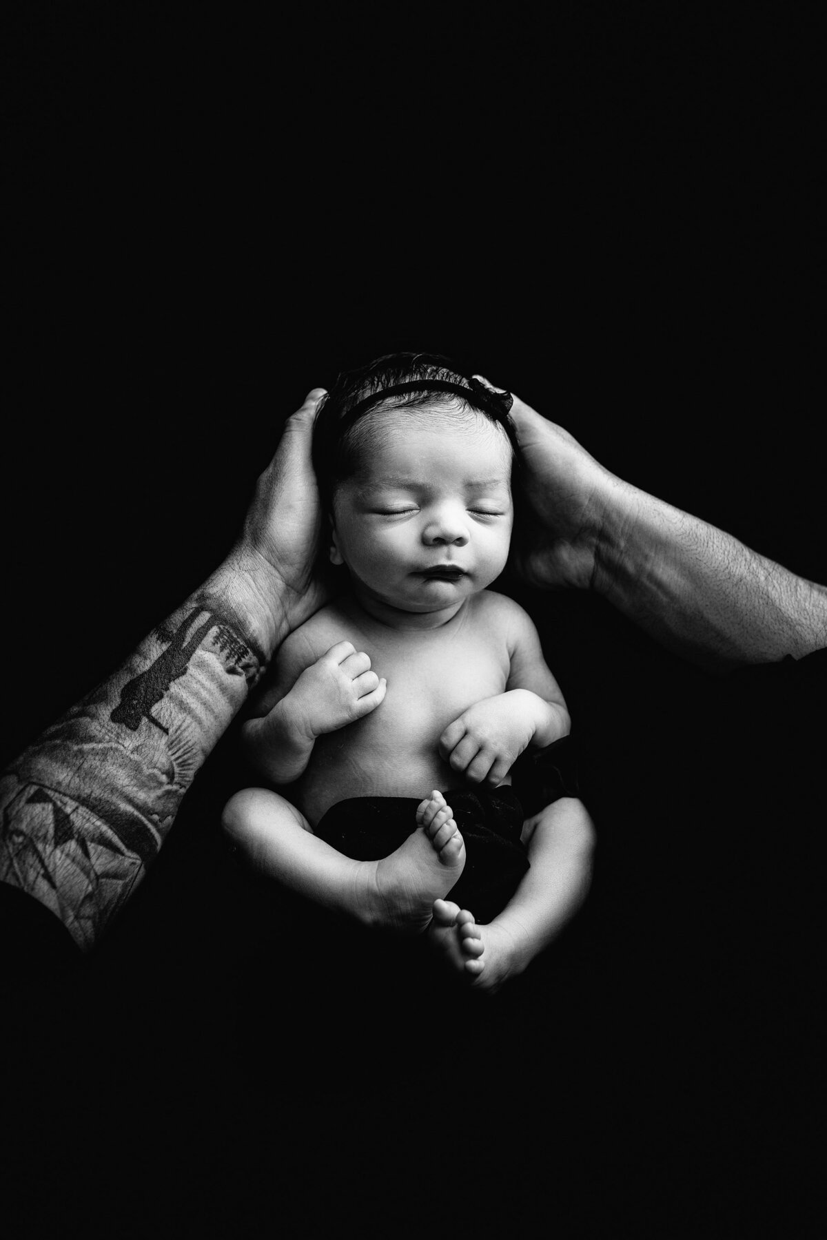 father holds his newborn daughter in a black and white photo