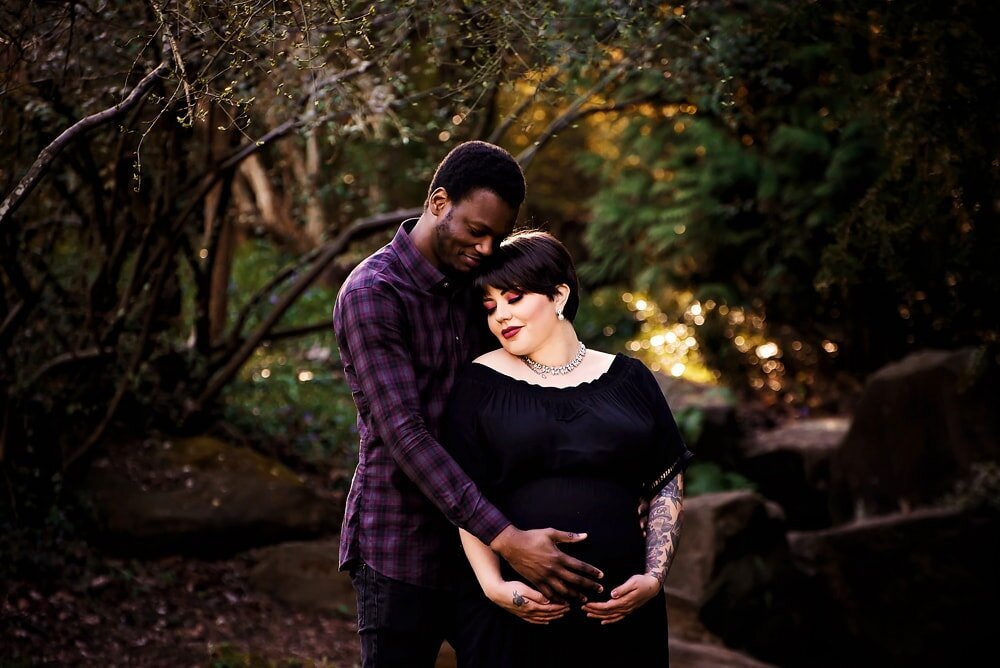 Pregnant woman and husband embracing during pregnancy photoshoot in Vancouver park