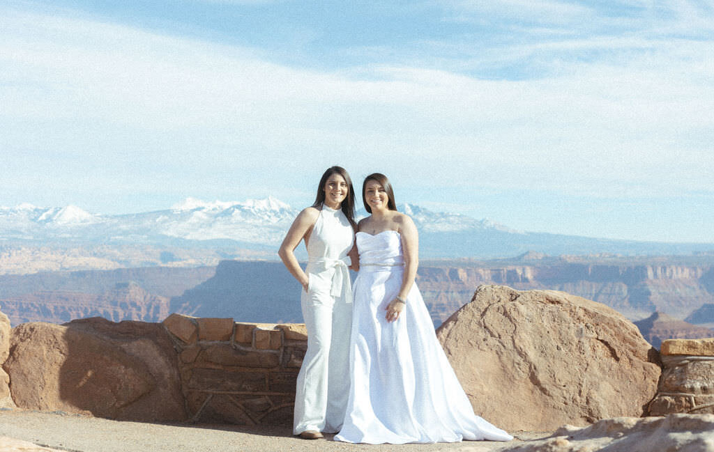 A newlywed couple standing together with a canyon behind them.