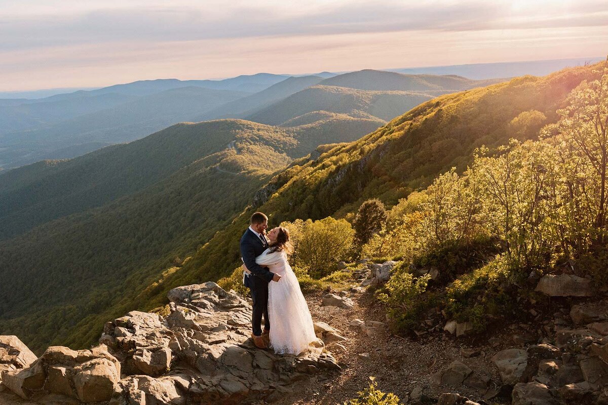 A bride and groom facing one another during  their Shenandoah Elopement. They are surrounded by the Blue Ridge Mountains, and the glow of sunrise.
