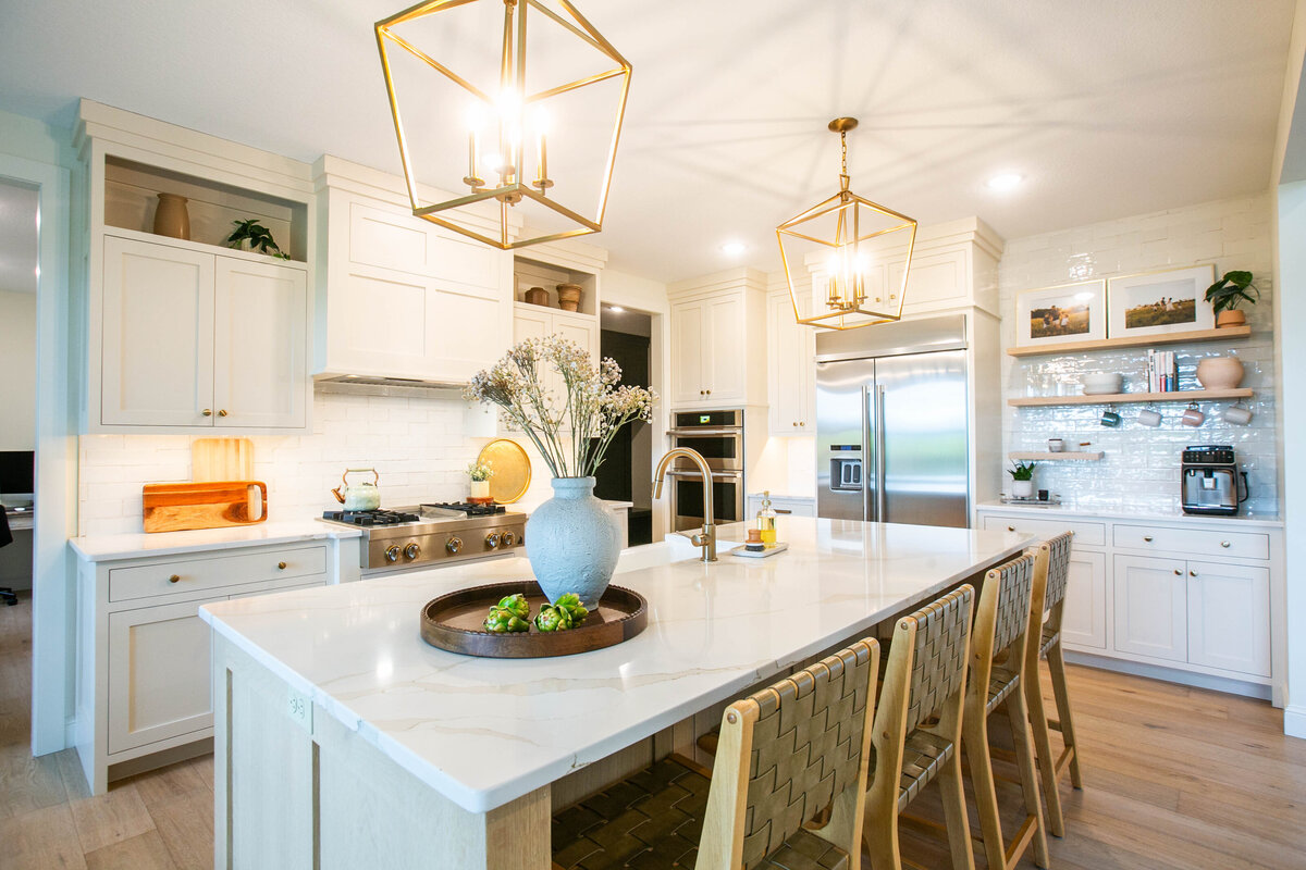 Open kitchen with white cabinets, large island, and quartz countertops in an Otsego custom home