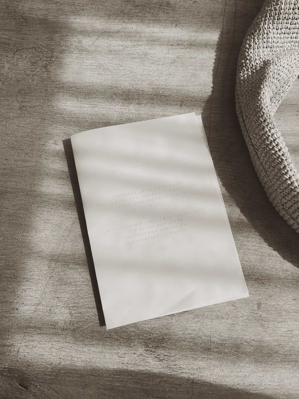 Close-up of a textured, light-colored surface with a partially visible notepad and a woven fabric, creating a soft, neutral aesthetic.