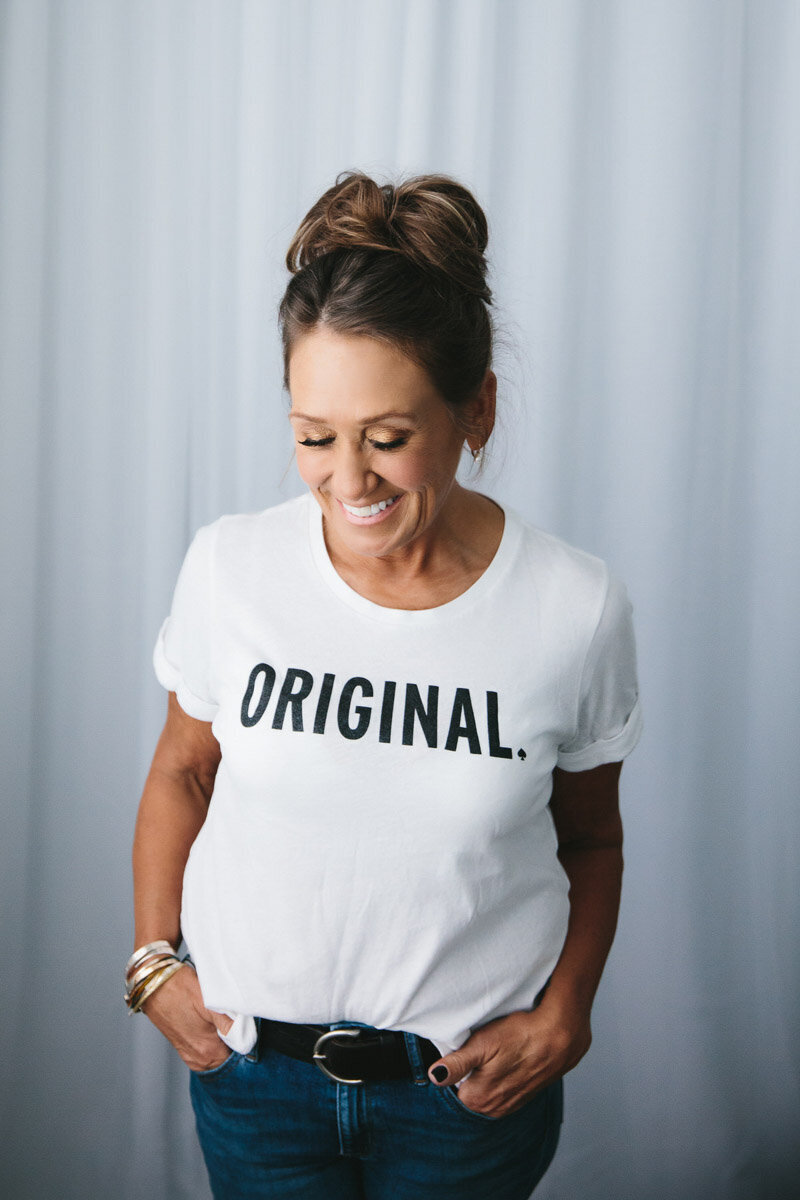 Woman smiling wearing a t shirt that reads "Original."