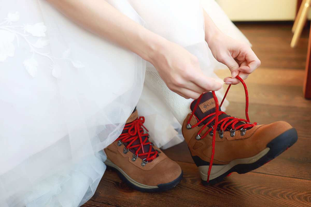 A bride eloping, putting her hiking boots on under her wedding dress.