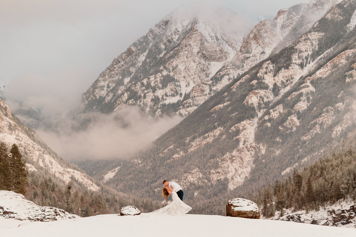 bride and groom kissing by mountain